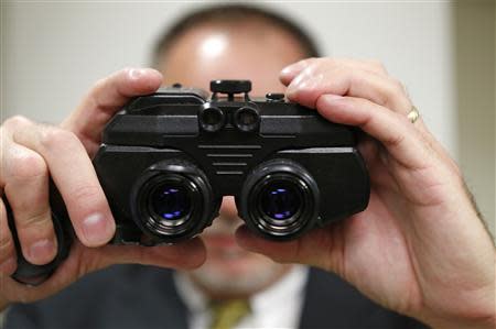 Craig Healy, the US government's chief law enforcement officer for counter-proflieration, holds up seized night vision goggles in his office at the Export Enforcement Coordination Center in northern Virginia November 21, 2013. REUTERS/Kevin Lamarque