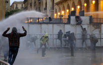 Anti-government protesters are sprayed by a water cannon as they clash with the riot police during ongoing protests in Beirut, Lebanon, Wednesday, Jan. 22, 2020. Lebanon's new government has held its first meeting a day after it was formed following a three-month political vacuum.(AP Photo/Bilal Hussein)