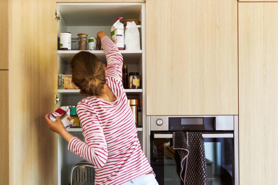 woman tidies up her cupboard in the kitchen