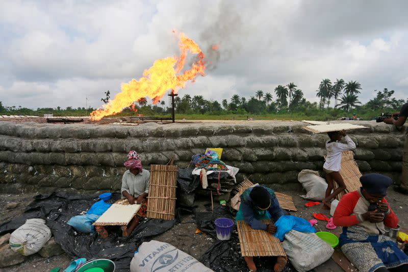 A family prepare tapioca behind sand barriers surrounding a gas flaring furnace at a flow station in Ughelli, Delta State