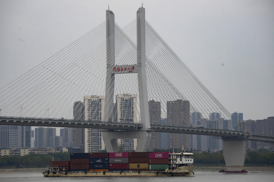 In this April 16, 2020, photo, a container ship past under the Second Wuhan Yangtze River Bridge on the Yangtze River in Wuhan in central China's Hubei province. Wuhan has been eclipsed by Shanghai, Hong Kong and other coastal cities since the ruling Communist Party set off a trade boom by launching market-style economic reforms in 1979. But for centuries before that, the city was one of the most important centers of an inland network of river trade that dominated China's economy and politics. (AP Photo/Ng Han Guan)