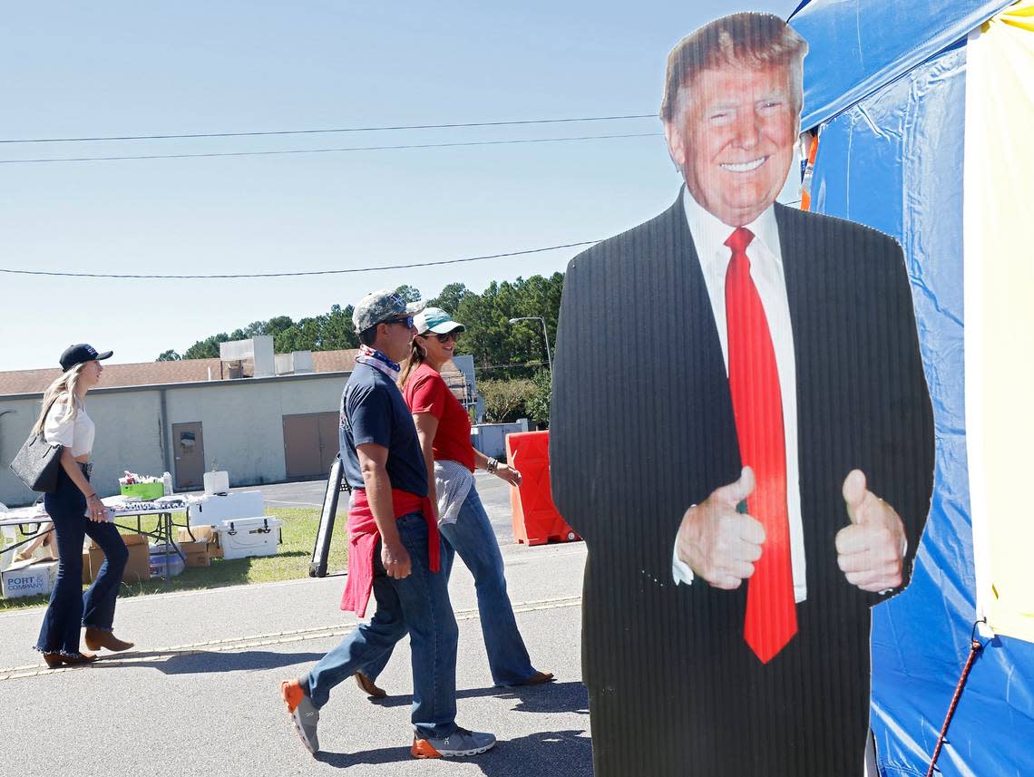 People walk past a cardboard cut-out of former president Donald Trump prior to a rally in Wilmington, N.C. on Friday, Sept. 23, 2022.