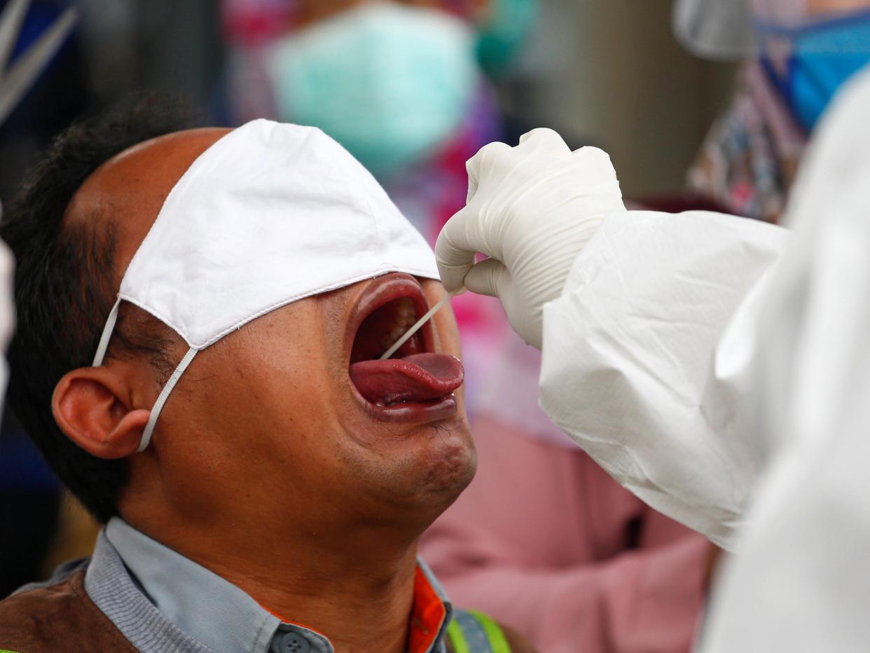 Healthcare workers take a swab sample from a passenger amid the coronavirus disease (COVID-19) outbreak, at a commuter train station in Bogor near Jakarta, Indonesia, May 11, 2020. REUTERS/Ajeng Dinar Ulfiana