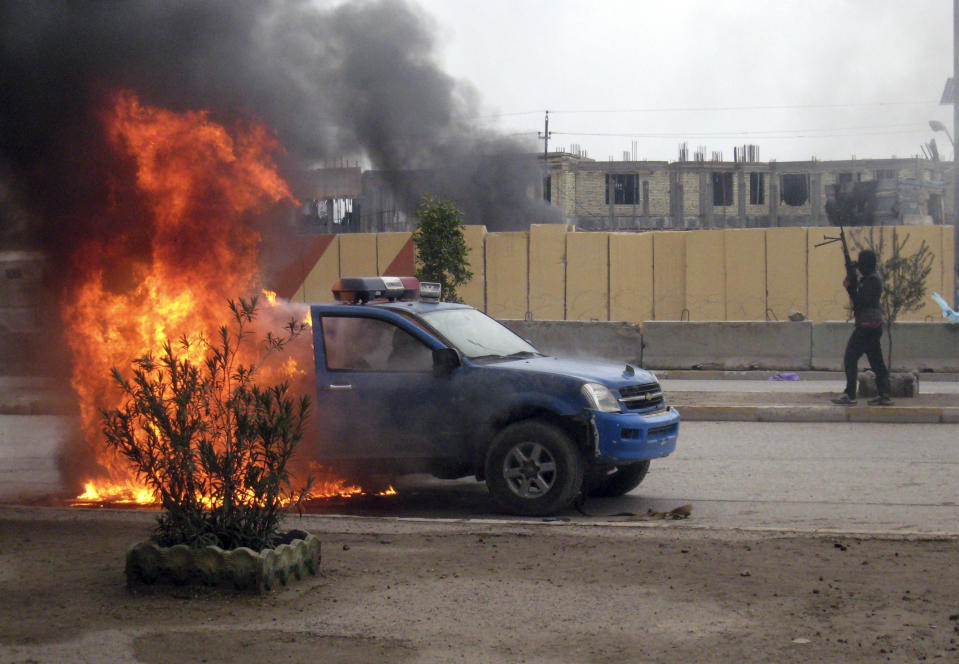 FILE - In this Wednesday Jan. 1, 2014, file photo, an al-Qaida fighter stands guard after setting fire to an Iraqi police truck in front of the provincial government headquarters in Fallujah, Iraq. More than a month after jihadist militants seized control of parts of Iraq’s western Anbar province, an unsettling realization is sinking in: Iraq’s government could face a tougher time beating back an insurgency there than the hard slog the Americans faced last decade. The reasons include a deep distrust of the government by Iraqi Sunnis, insufficient resources, sectarian tensions enflamed by the war in Syria and divisions among the tribes that make up Anbar’s social fabric. (AP Photo, File)