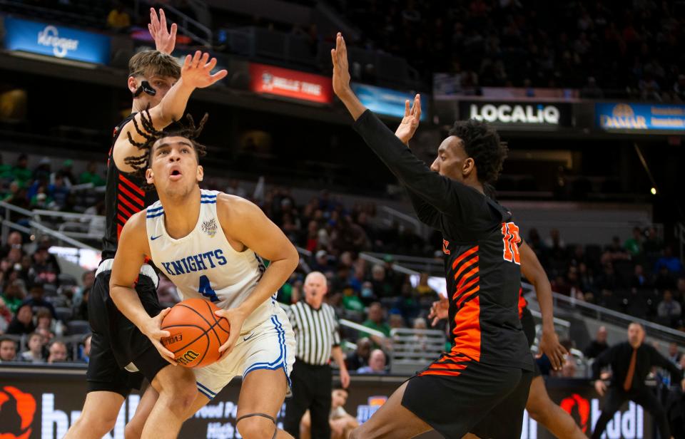 Marian's Zion Rhoades (4) looks for a shot with pressure from Beech Grove's Cam Brown (5) and Jaleel Edwards (10) during the 3A boys basketball state championship game on Saturday, March 26, 2022, at Gainbridge Fieldhouse in Indianapolis. 