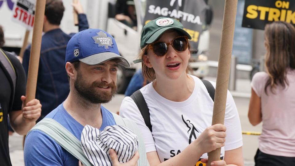 Daniel Radcliffe carrying baby boy with Erin Darke holding sign