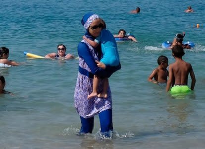 A woman wearing a burkini walks in the water August 27, 2016 on a beach in Marseille, France, the day after the country's highest administrative court suspended a ban on full-body burkini swimsuits that has outraged Muslims and opened divisions within the government, pending a definitive ruling.  REUTERS/Stringer