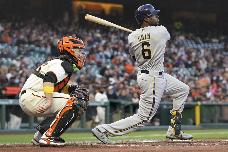 Milwaukee Brewers' Lorenzo Cain (6) watches his two-run single in front of San Francisco Giants catcher Buster Posey during the second inning of a baseball game in San Francisco, Wednesday, Sept. 1, 2021. (AP Photo/Jeff Chiu)