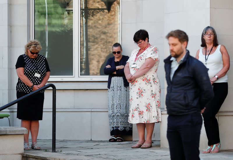 People stand by a police cordon observing a minute's silence following multiple stabbings in Reading