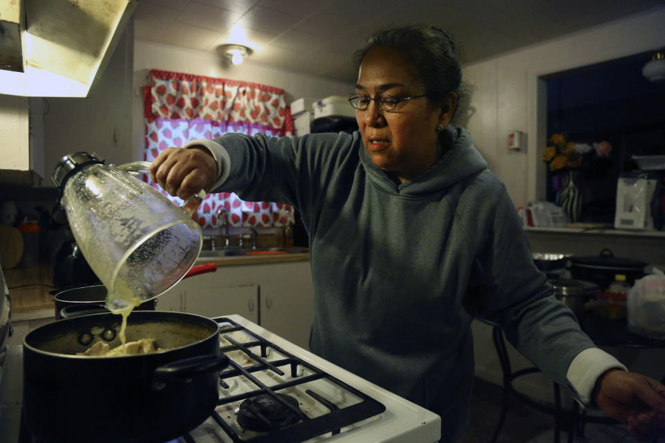 Silvia De Leon pours a handmade salsa into a pot of chicken after returning home from a local church food pantry in Noel, Mo., Saturday, Nov. 21, 2020. After contracting the coronavirus in late June, De Leon was unable to work and her medical bills mounted. For the past five months, she has utilized the pantry every week to sustain the household she shares with her retired husband. (AP Photo/Jessie Wardarski)