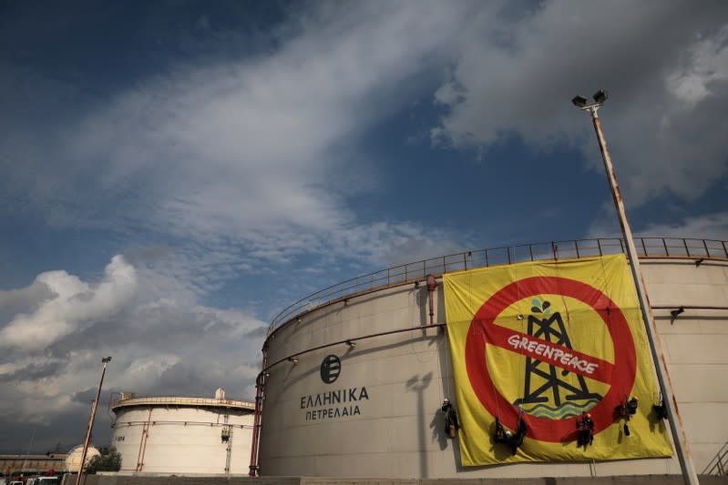 Greenpeace activists hang from an oil tank at the Hellenic Petroleum refineries in Aspropyrgos near Athens