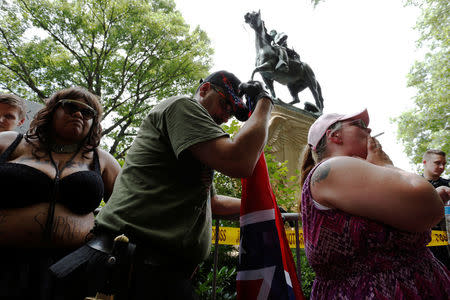 A woman (R) who supports Confederate symbols and monuments relaxes with a cigarette after she and her husband (C) exchanged words with a counter-protester as they wait for members of the Ku Klux Klan to rally in support of Confederate monuments, such as the statue of General Stonewall Jackson behind them, in Charlottesville, Virginia, U.S. July 8, 2017. REUTERS/Jonathan Ernst