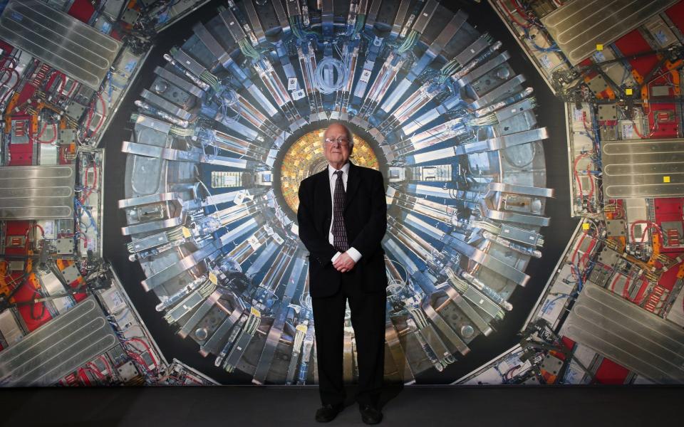 Prof Higgs in front of a photograph of the Large Hadron Collider