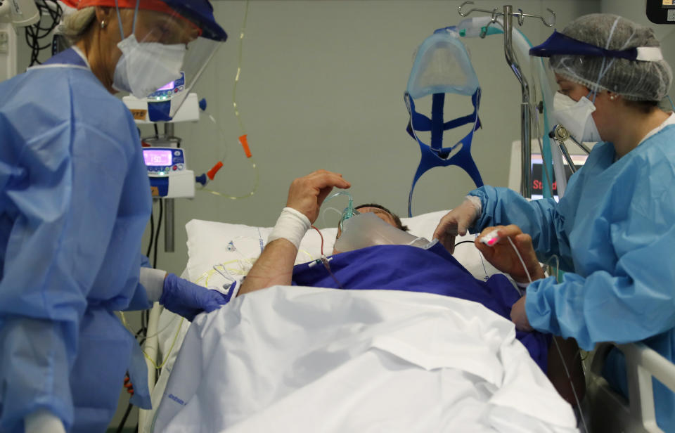 Medical staff members tend to a patient in the COVID-19 Intensive Care Unit of the Papa Giovanni XIII hospital in Bergamo, Italy, Thursday, March 18, 2021. Bergamo’s state-of-the-art Pope John XXIII Hospital verged on collapse last March: as army trucks ferried virus dead from the city’s over-taxed crematoria, doctors struggled to care for 600 COVID patients, 100 in intensive care. One year later, the picture is much improved: the hospital now is treating fewer than 200 virus patients, just one quarter of those requiring intensive care. (AP Photo/Antonio Calanni)