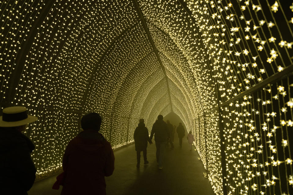 People walking through an illuminated tunnel with star-like lights covering the walls and ceiling