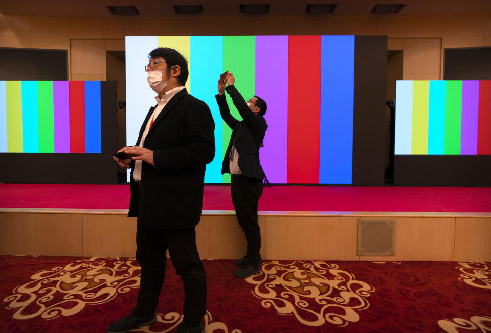 Staff members take smartphone photos before a remote video press conference by Chinese Foreign Minister Wang Yi held on the sidelines of the annual meeting of China's National People's Congress (NPC) in Beijing, Sunday, March 7, 2021. (AP Photo/Mark Schiefelbein)