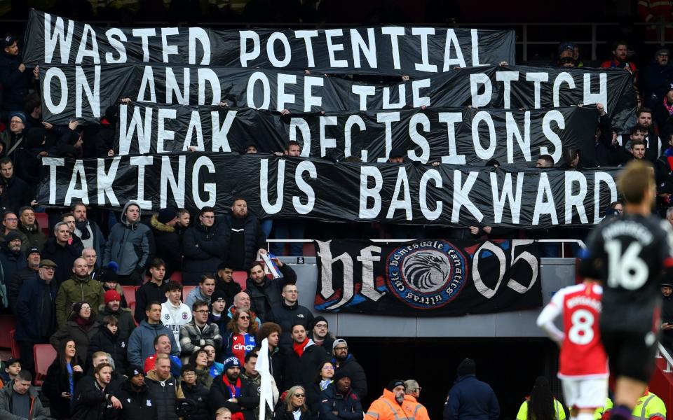 Crystal Palace fans hold a banner in protest during the Premier League match between Arsenal FC and Crystal Palace at Emirates Stadium on January 20, 2024 in London, England