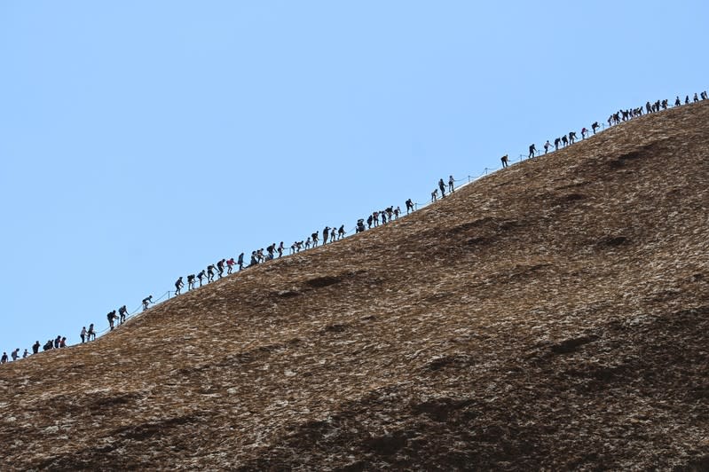 Tourists climb Uluru, formerly known as Ayers Rock, at Uluru-Kata Tjuta National Park in the Northern Territory