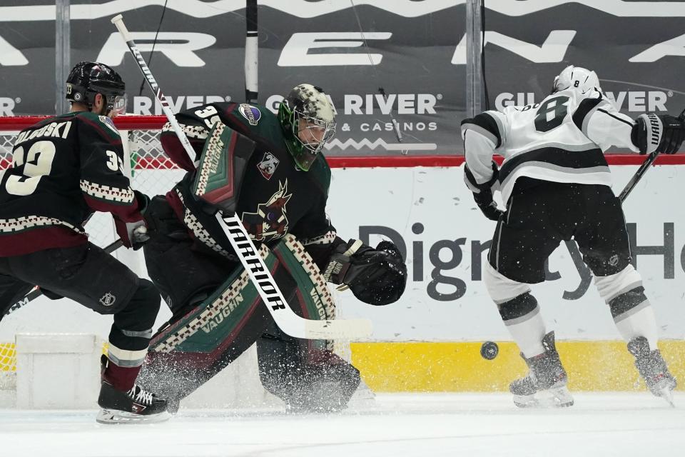Arizona Coyotes goaltender Darcy Kuemper (35) makes a save on a shot by Los Angeles Kings defenseman Drew Doughty (8) as Coyotes defenseman Alex Goligoski (33) arrives to defend during the first period of an NHL hockey game Monday, May 3, 2021, in Glendale, Ariz. (AP Photo/Ross D. Franklin)