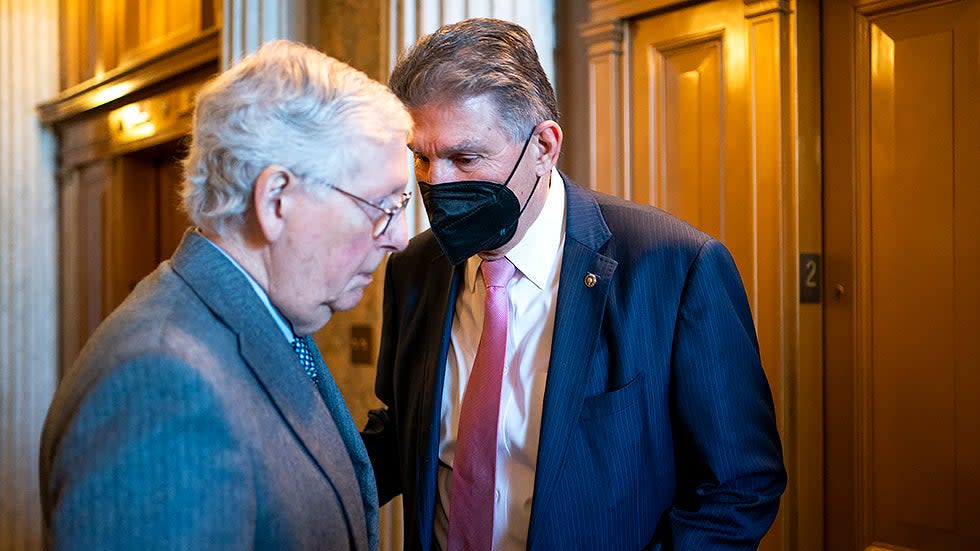 Minority Leader Mitch McConnell (R-Ky.) listens to Sen. Joe Manchin (D-W.Va.) outside the Senate Chamber during a vote prior to the weekly policy luncheons on Tuesday, February 15, 2022.