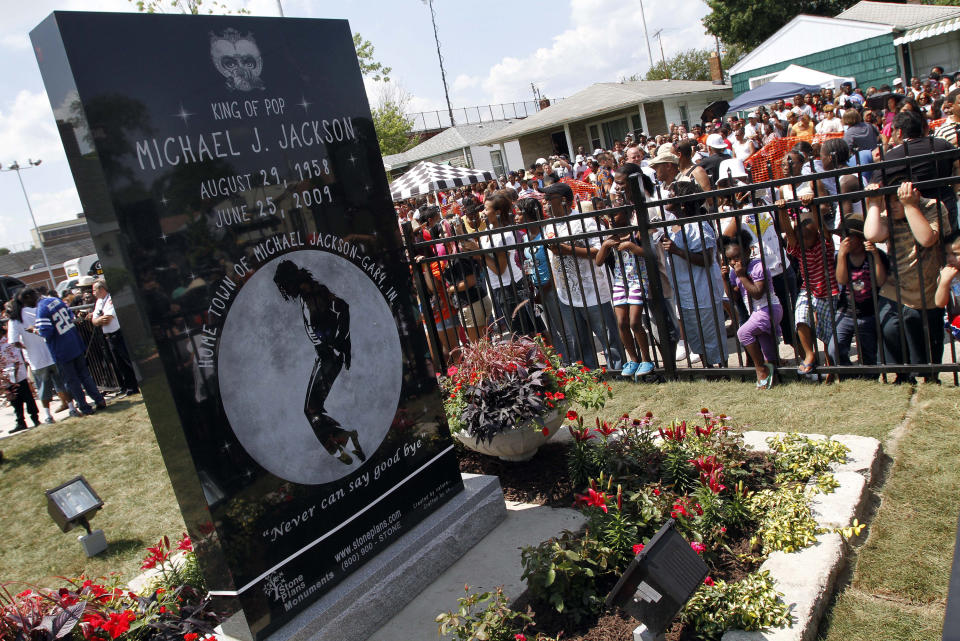 FILE - In this June 25, 2010 file photo, Michael Jackson fans gather around a monument that was unveiled in Gary, Ind., on the first anniversary of the pop icon's death. As the 10th anniversary of Jackson’s death approaches, experts say his music legacy is still going strong despite the documentary’s detailed abuse allegations. (AP Photo/John Smierciak, File)