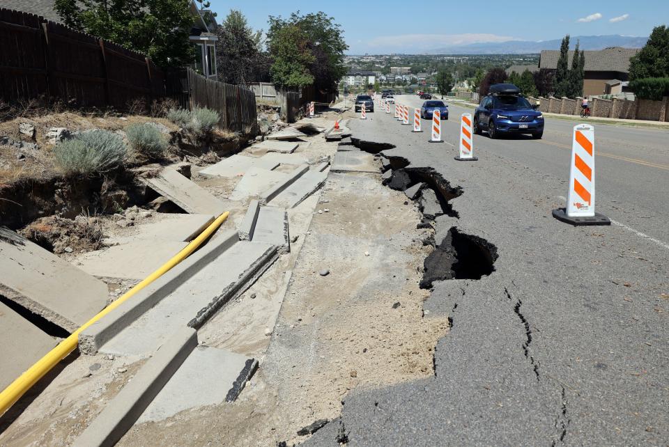 Vehicles move past a sinkhole on Bangerter Highway after flooding washed out a section of the road in Draper on Friday, Aug. 4, 2023. Draper Mayor Troy Walker declared a state of emergency due to flooding. | Kristin Murphy, Deseret News