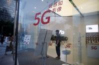 A woman wearing a face mask enters a Huawei store with 5G signs at a shopping mall, in Beijing