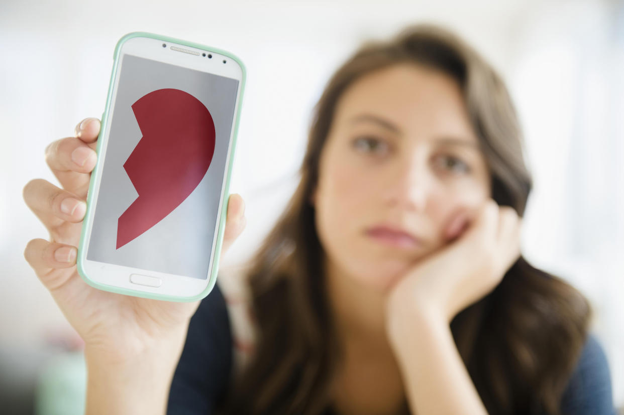 Woman showing image of broken heart on her smartphone