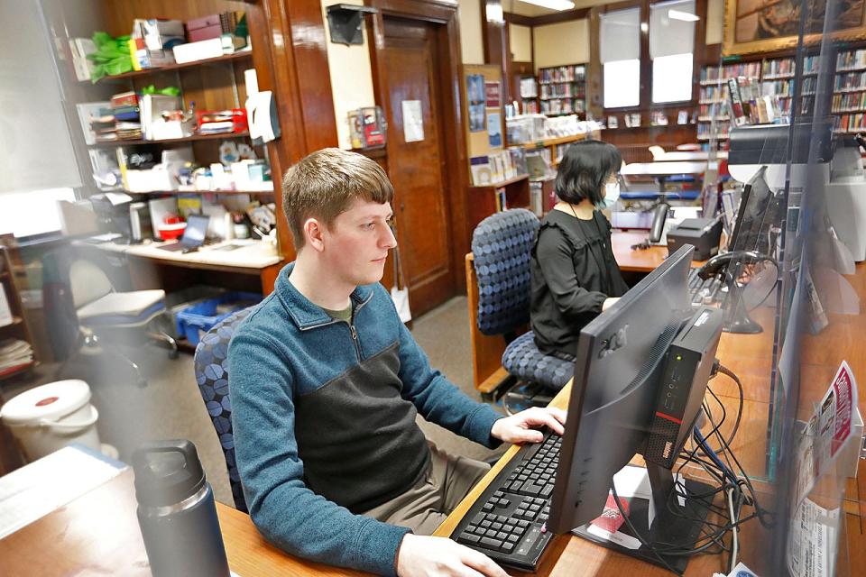 Assistant librarians Shawn Ramsay and Lani Parker work at the checkout desk of the Wollaston library branch in Quincy on Monday, Jan. 23, 2023.