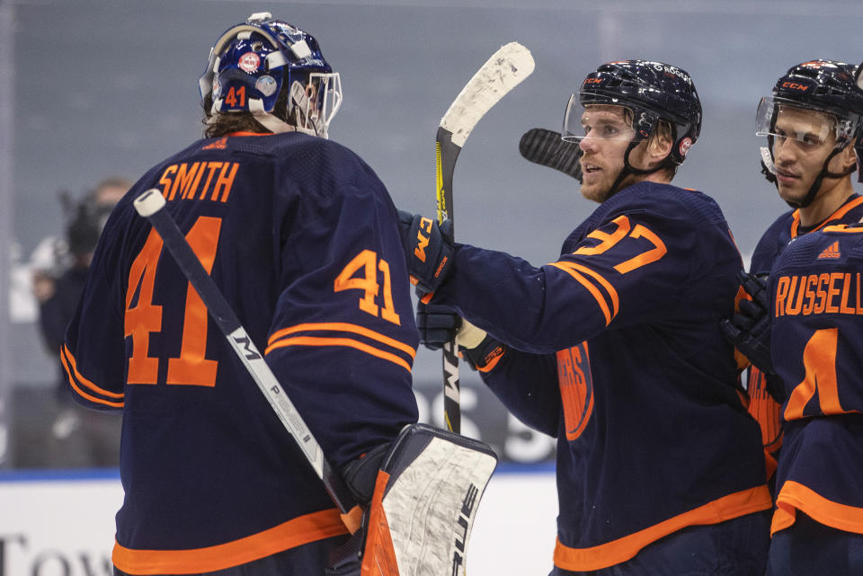 Edmonton Oilers goalie Mike Smith (41) and teammate Connor McDavid (97) celebrate the Oilers' win over the Calgary Flames in an NHL hockey game Saturday, March 6, 2021, in Edmonton, Alberta. (Jason Franson/The Canadian Press via AP)