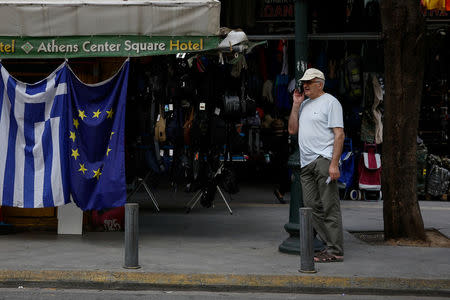 A man stands next to a kiosk selling Greek and EU flags in Athens, Greece, June 21, 2018.REUTERS/Costas Baltas