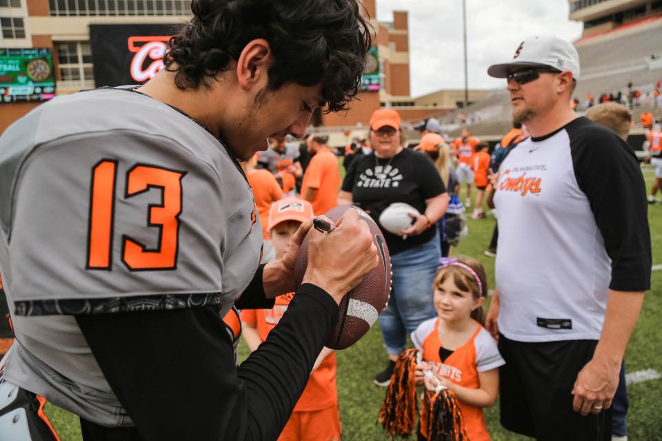 OSU quarterback Garret Rangel (13) sings the ball for a young fan after the Cowboys' spring scrimmage on April 23.