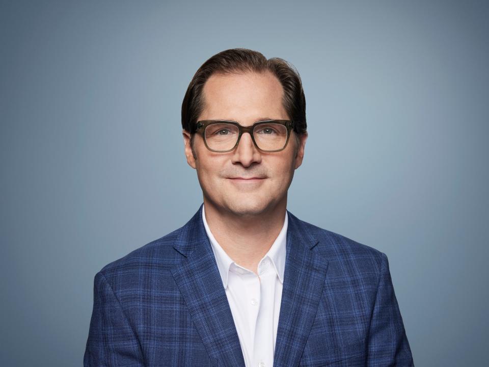 White man in glasses with blue jacket and white shirt