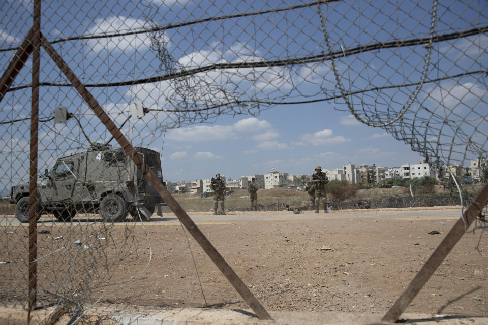 Israeli soldiers guard a damaged section of the Israeli separation fence, that is used by Palestinian laborers to cross into Israel, in the West Bank village of Jalameh, near Jenin, Monday, Sept. 6, 2021. Israel launched a massive manhunt in the country's north and the occupied West Bank early Monday after six Palestinian prisoners tunneled out of their cell and escaped overnight from a high-security facility in an extremely rare breakout. (AP Photo/Nasser Nasser)