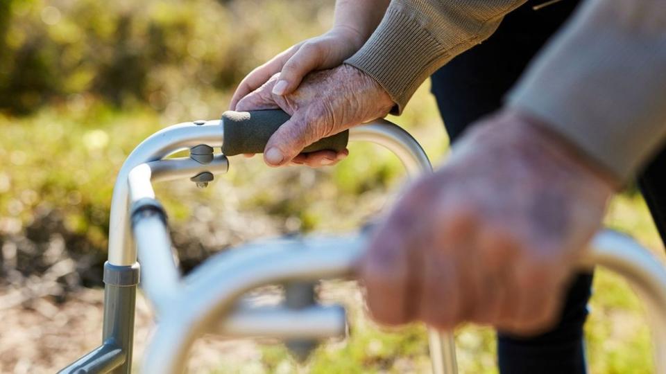 Las manos de un hombre anciano apoyándose en un caminador