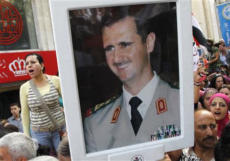 Supporters of Syrian President Bashar al-Assad's hold pictures of al-Assad during a rally at al-Sabaa Bahrat square in Damascus October 12, 2011. REUTERS/ Khaled al-Hariri