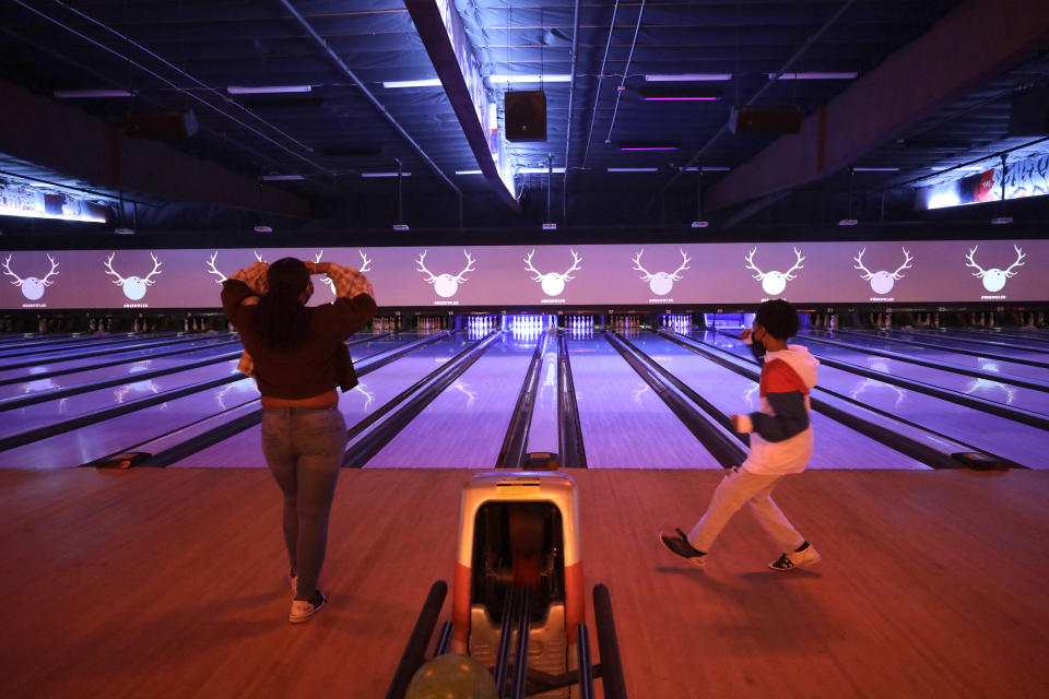 WESTCHESTER, CA - APRIL 06: Bryce Henderson, 11 right, celebrates a missed roll after heckling his sister, Jaylin, 16, during a competitive game at Bowlero Los Angeles bowling alley in Westchester on Tuesday, April 6, 2021. The center saw customers again after being closed for a year. Safety protocols include facemasks, plexiglass dividers between stations and 25 percent capacity. (Myung J. Chun / Los Angeles Times via Getty Images)