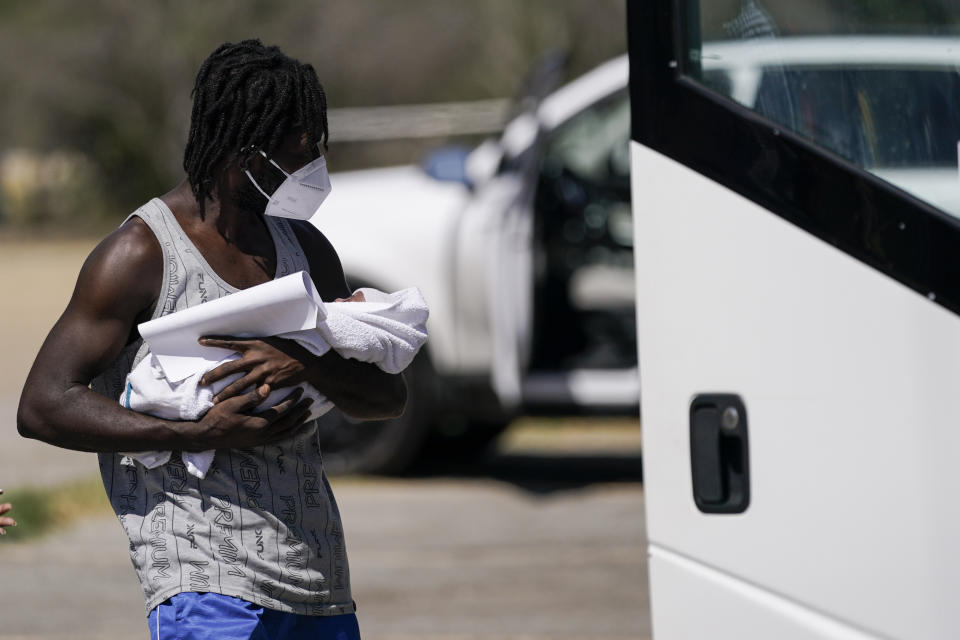 A migrant holds a baby while boarding a bus to Houston at a humanitarian center after they were released from United States Border Patrol upon crossing the Rio Grande and turning themselves in seeking asylum, Wednesday, Sept. 22, 2021, in Del Rio, Texas. (AP Photo/Julio Cortez)