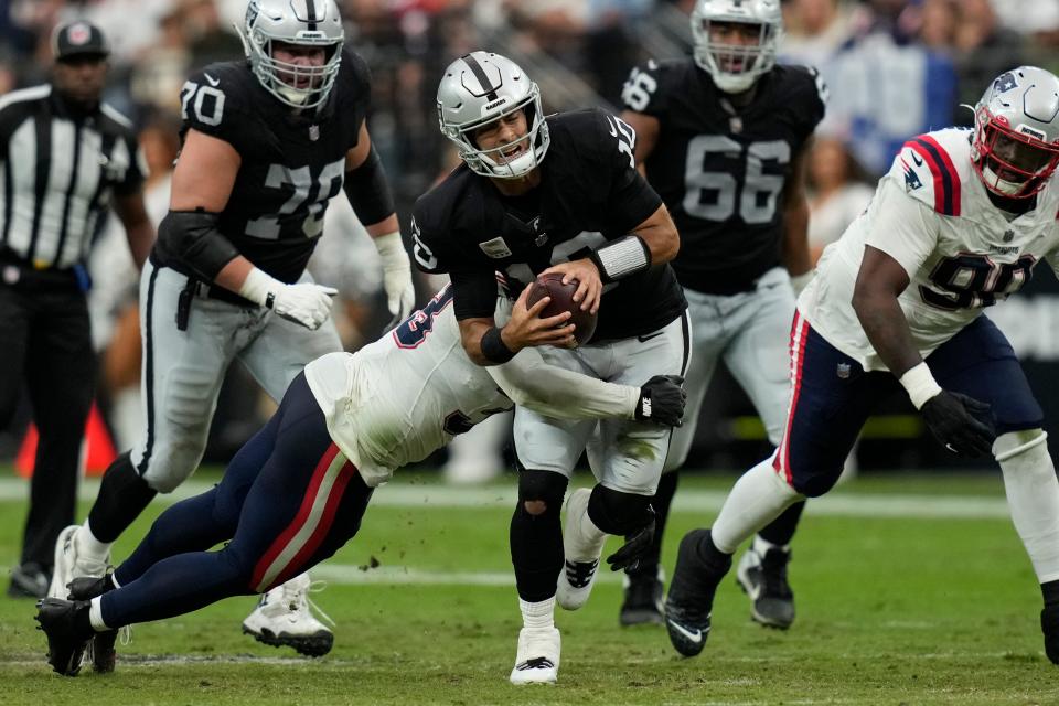 Las Vegas Raiders quarterback Jimmy Garoppolo, center, is hauled down by New England Patriots linebacker Anfernee Jennings during the first half of an NFL football game Sunday, Oct. 15, 2023, in Las Vegas.