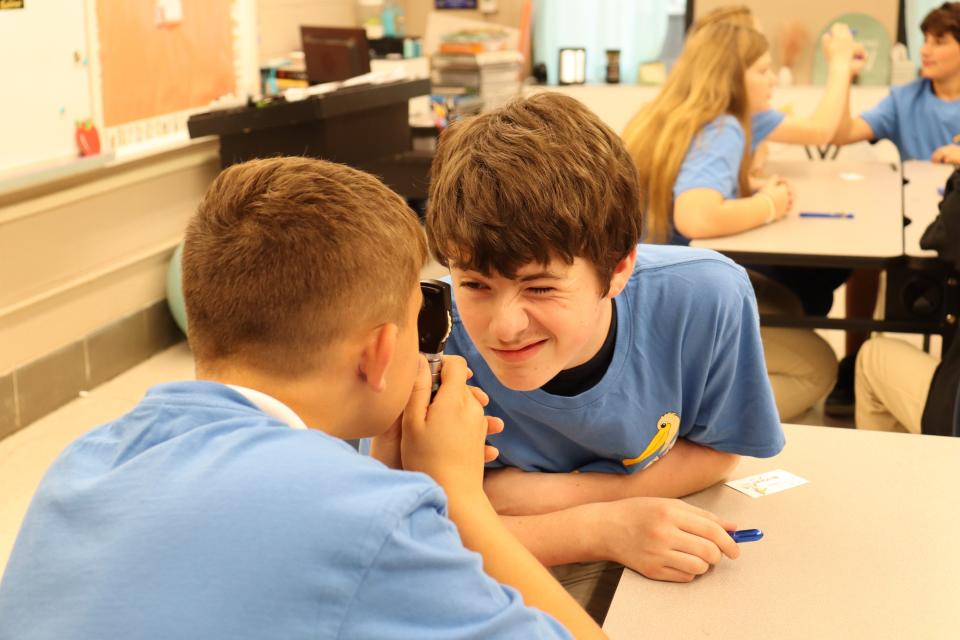 Declin McClin, 13, squints as classmate Duncan DeSoto looks into his eye with an ophthalmoscope during a MedStart class on Oct. 11 at Poland Junior High School.