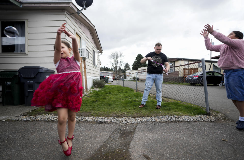 Gadiel Galvez, 22, at center, prepares to blow more bubbles as his sisters Elizama Galvez, 4, at left, and Dafne Galvez, 10, play outside his home at Bob’s and Jamestown Homeowners Cooperative, a resident-owned mobile home park in Lakewood, Wash., on Saturday, March 25, 2023. When residents learned the park’s owner was looking to sell, they formed a cooperative and bought it themselves amid worries it would be redeveloped. Since becoming owners in September 2022, residents have worked together to manage and maintain the park. (AP Photo/Lindsey Wasson)