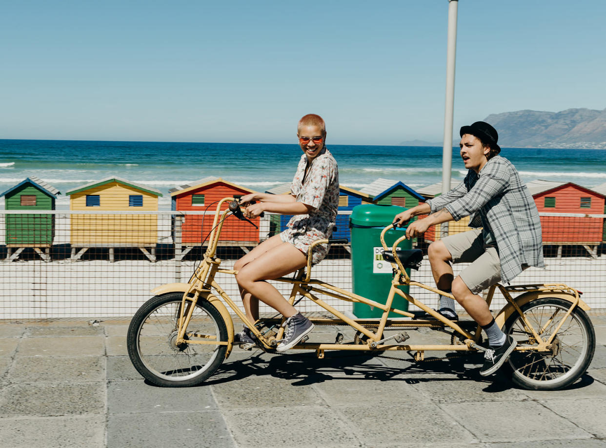 Young couple riding a tandem bicycle on a boardwalk (Hello World / Getty Images)