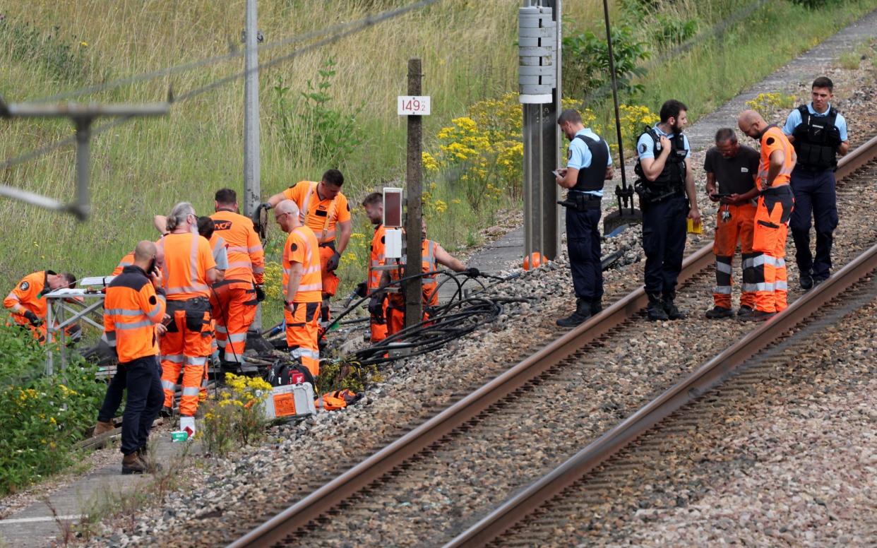 Men in hi-vis suits and police officers work on a rail track