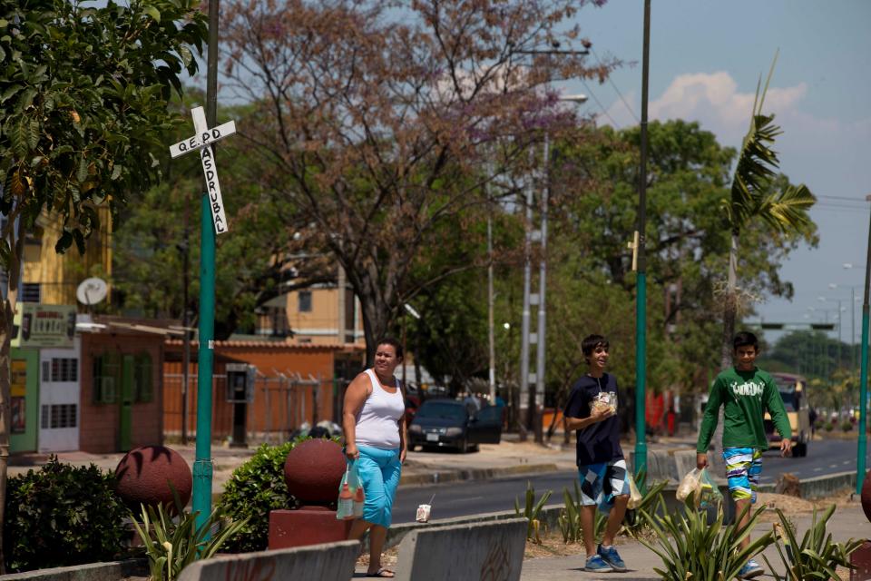 In this photo taken on Saturday, March 15, 2014. Residents walks near to a opposition protest at Isabelica neighborhood outside Valencia , Venezuela. The people of the poor district of La Isabelica were made to pay for taking to the streets in anti-government protests. More than a dozen masked men on motorcycles roared through, shooting up a barricade and killing a university student and a 42-year-old man painting his house. (AP Photo/Fernando Llano)