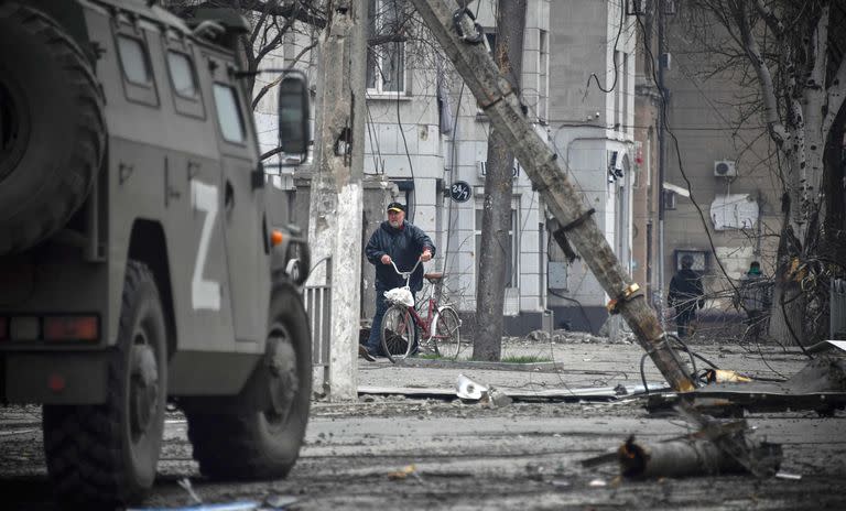 Un hombre camina con una bicicleta en el centro de Mariupol el 12 de abril de 2022, mientras las tropas rusas intensifican una campaña para tomar la estratégica ciudad portuaria, parte de una anticipada embestida masiva en todo el este de Ucrania, mientras el presidente de Rusia defiende desafiantemente la guerra contra el vecino ruso.