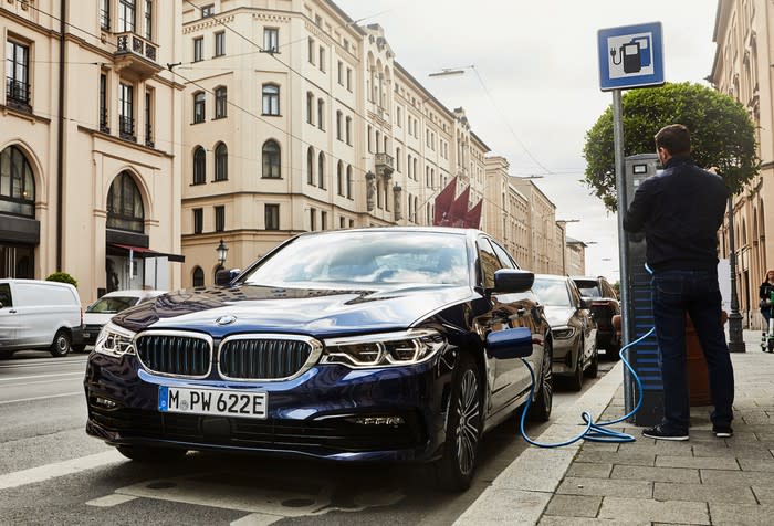 A BMW plug-in hybrid sedan, parked next to a charger on a German city street.