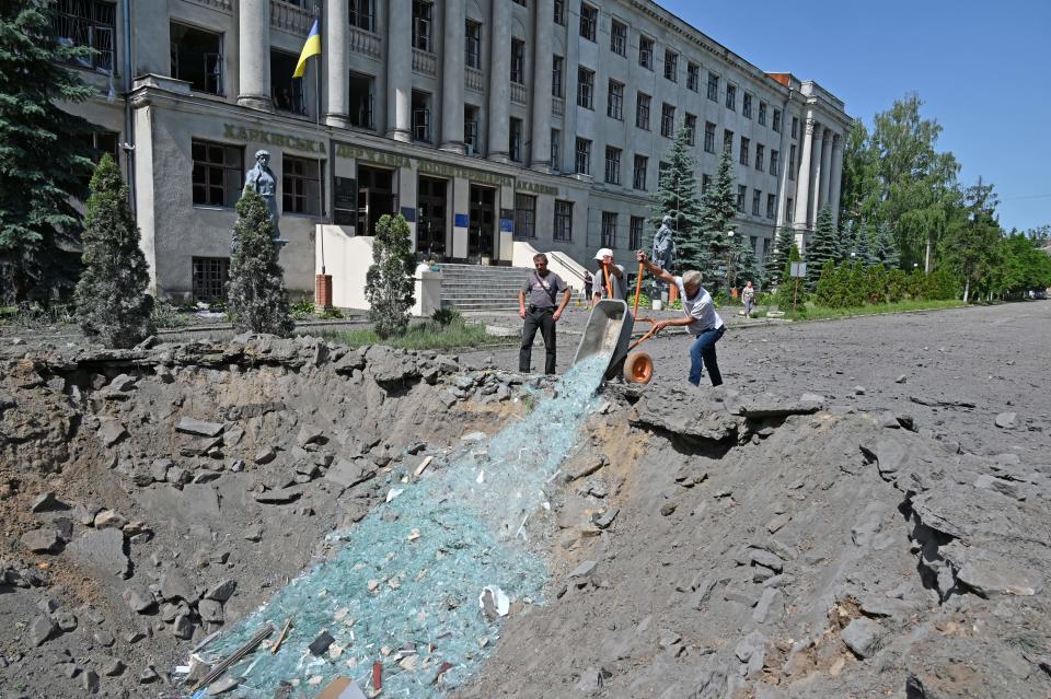 Workers of the Liubotinsky Lyceum of Railway Transport and local residents dismantle the ruins of an administrative building, as result of the explosion of a Russian rocket, in Lyubotyn, Kharkiv region (AFP via Getty Images)