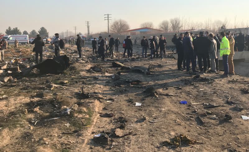 Rescue team members check the debris from the Ukraine International Airlines plane that crashed after take-off from Iran's Imam Khomeini airport, on the outskirts of Tehran