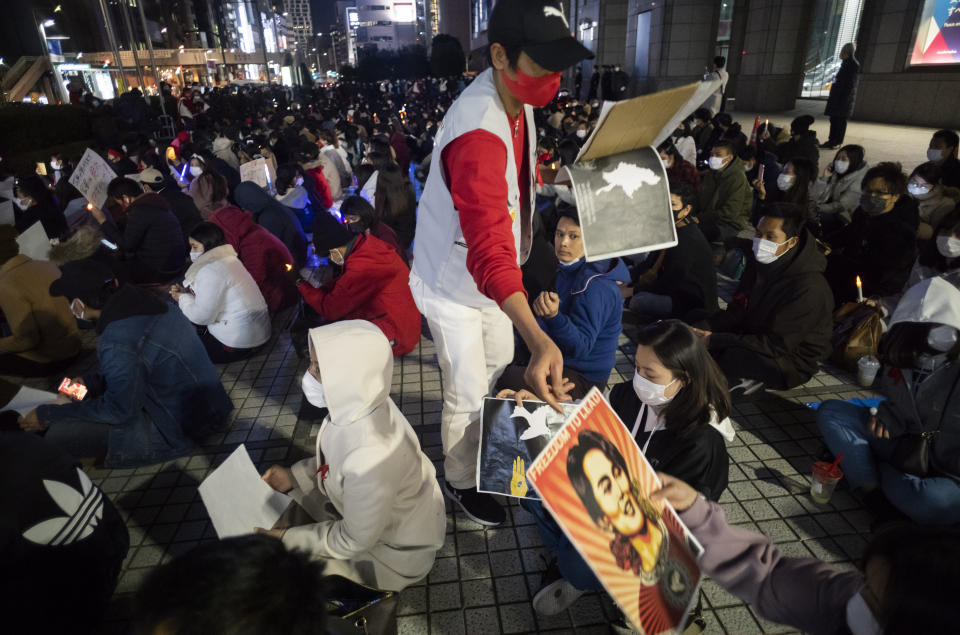 A member of a protest group called "WeLoveMyanmar" provides posters during a demonstration against the Myanmar military, in front of the United Nations University in Tokyo on Thursday, Feb. 11, 2021. (AP Photo/Hiro Komae)