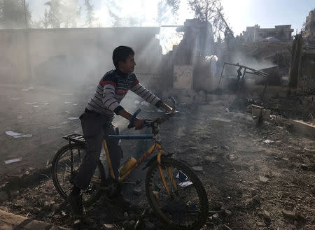 A Palestinian boy rides a bicycle near a militant target that was hit in an Israeli airstrike in the northern Gaza Strip December 9, 2017. REUTERS/Mohammed Salem